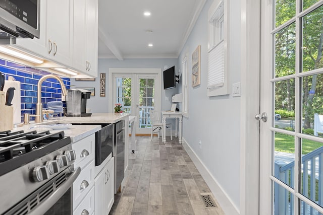 kitchen featuring visible vents, light wood-style flooring, stainless steel appliances, decorative backsplash, and french doors