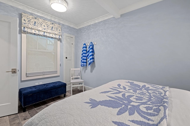 bedroom featuring beamed ceiling, baseboards, and wood finish floors