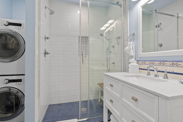 full bathroom featuring vanity, stacked washer and dryer, and a shower stall