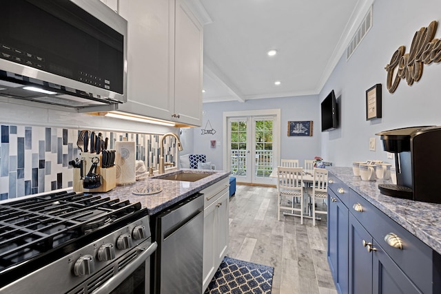 kitchen with visible vents, backsplash, crown molding, appliances with stainless steel finishes, and a sink