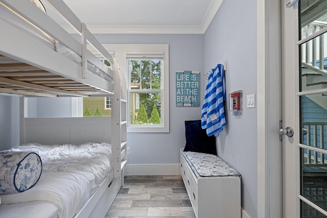 bedroom with baseboards, crown molding, and light wood finished floors