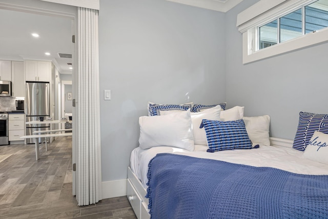 bedroom featuring visible vents, wood finished floors, freestanding refrigerator, recessed lighting, and crown molding