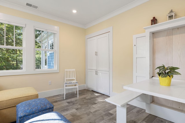 living area featuring visible vents, a healthy amount of sunlight, wood finished floors, and ornamental molding