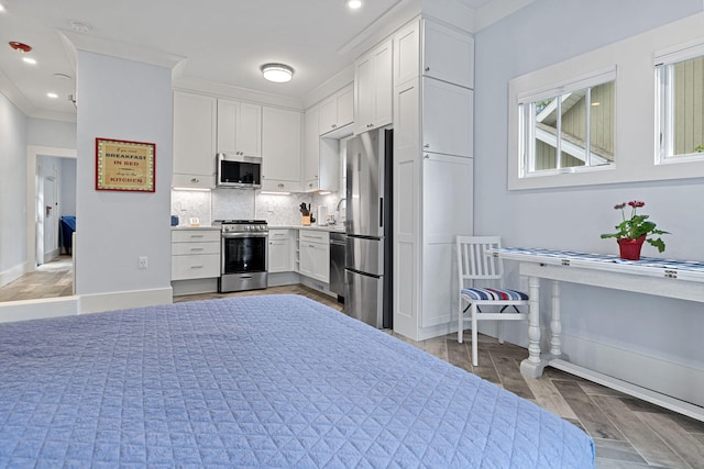 kitchen with baseboards, light countertops, decorative backsplash, appliances with stainless steel finishes, and white cabinets