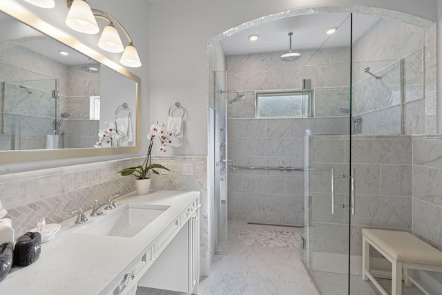 bathroom featuring a shower stall, vanity, wainscoting, marble finish floor, and tile walls