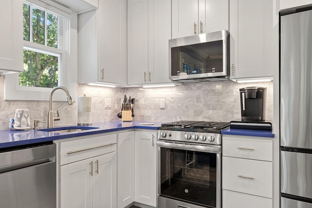 kitchen featuring a sink, white cabinetry, backsplash, and stainless steel appliances