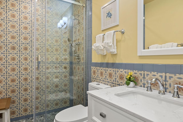 full bath featuring vanity, a shower stall, wainscoting, tile walls, and toilet