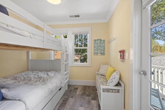 bedroom featuring visible vents, baseboards, wood finished floors, and crown molding