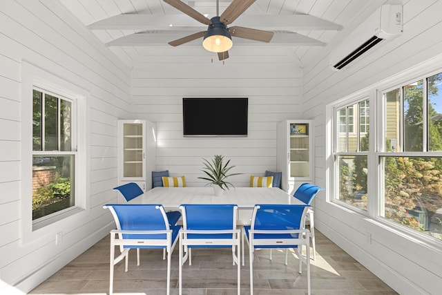 sunroom with lofted ceiling with beams, an AC wall unit, a ceiling fan, and a healthy amount of sunlight
