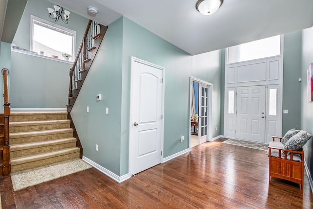foyer entrance with a notable chandelier, baseboards, stairs, and dark wood-style flooring