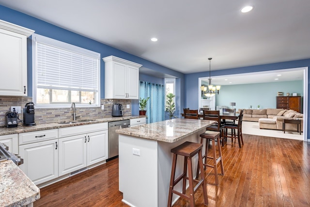 kitchen featuring backsplash, a breakfast bar, dishwasher, a sink, and dark wood-style flooring