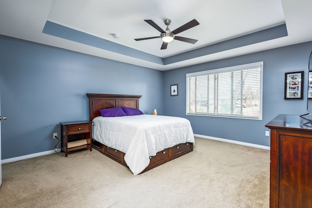 carpeted bedroom featuring a ceiling fan, baseboards, and a raised ceiling