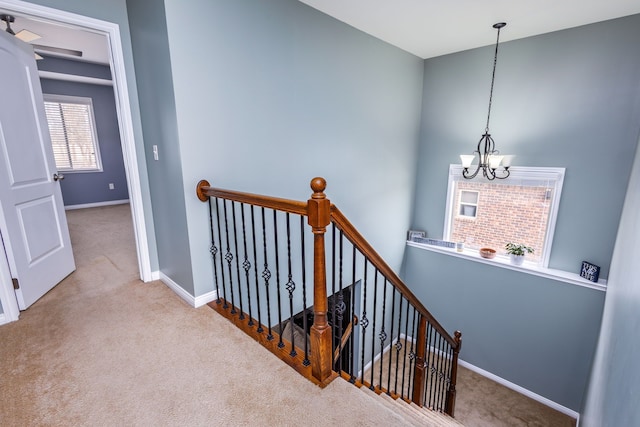 stairs featuring an inviting chandelier, carpet floors, and baseboards