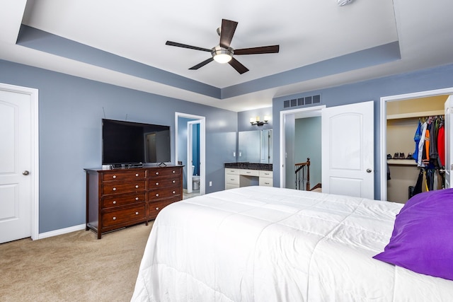 bedroom with a tray ceiling, baseboards, visible vents, and light colored carpet