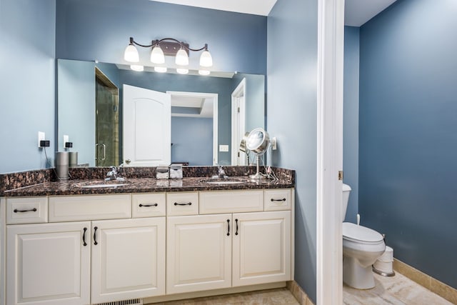 bathroom featuring baseboards, toilet, a stall shower, and a sink