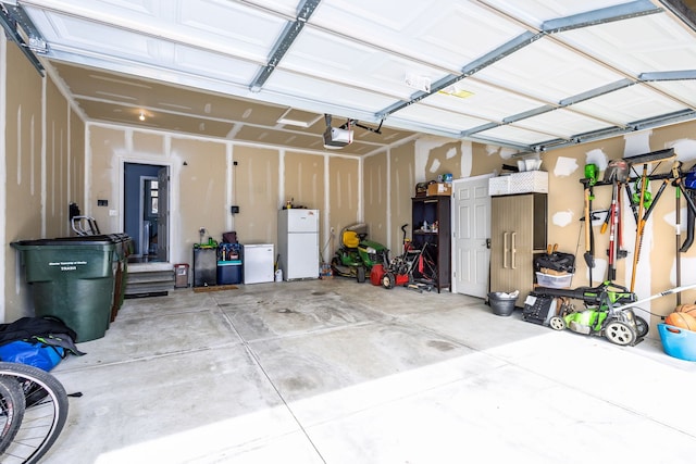 garage with freestanding refrigerator and a garage door opener