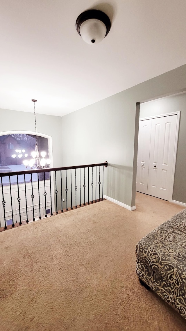 hall with carpet floors, baseboards, and a notable chandelier