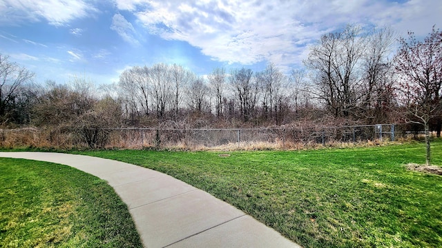 view of home's community with a lawn and fence