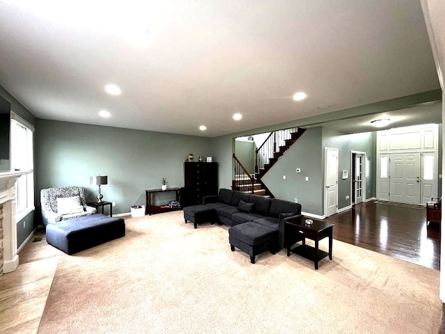 carpeted living area with recessed lighting, baseboards, stairs, and a fireplace with flush hearth