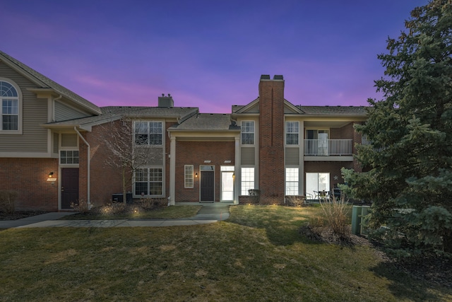 view of front facade featuring a front yard, brick siding, and a chimney