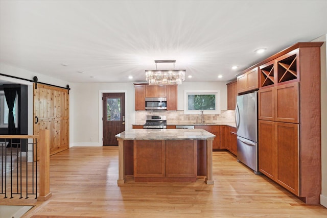 kitchen with plenty of natural light, a sink, appliances with stainless steel finishes, a barn door, and a center island