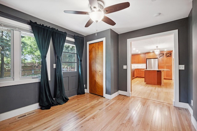 empty room with light wood-style flooring, baseboards, visible vents, and ceiling fan