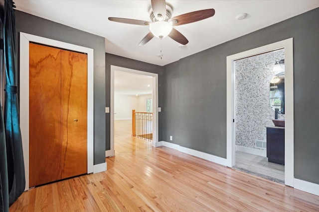 empty room featuring visible vents, light wood-style flooring, baseboards, and a ceiling fan