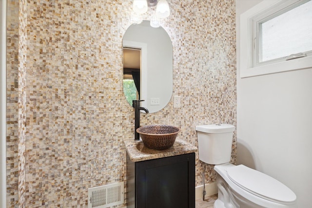 bathroom featuring vanity, toilet, visible vents, and plenty of natural light