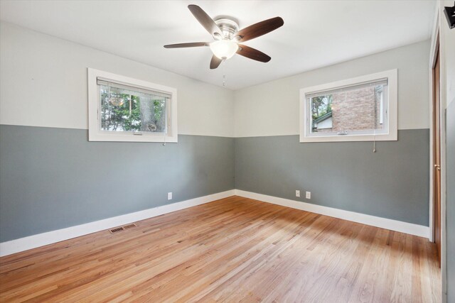 spare room with a healthy amount of sunlight, visible vents, light wood finished floors, and baseboards