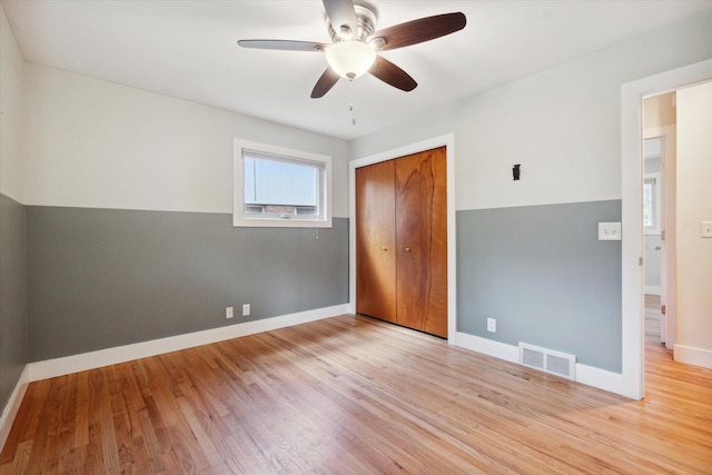 unfurnished bedroom featuring a ceiling fan, baseboards, visible vents, light wood finished floors, and a closet