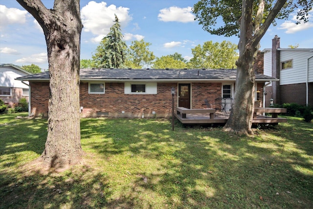 back of property with brick siding, a lawn, and a deck