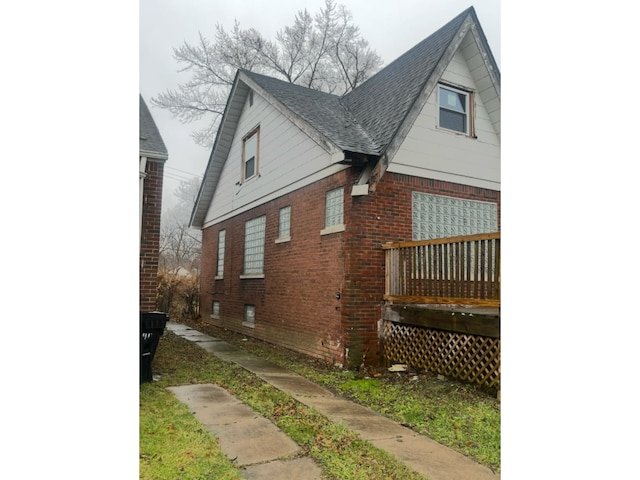 view of home's exterior with brick siding and a shingled roof