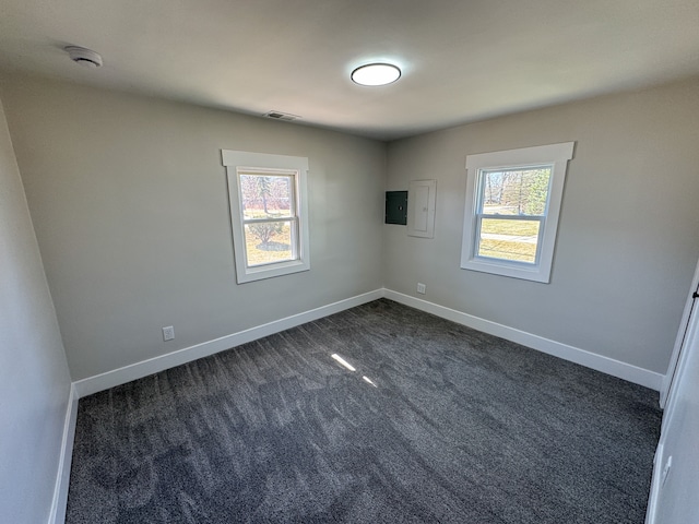 empty room featuring baseboards, dark colored carpet, visible vents, and a wealth of natural light