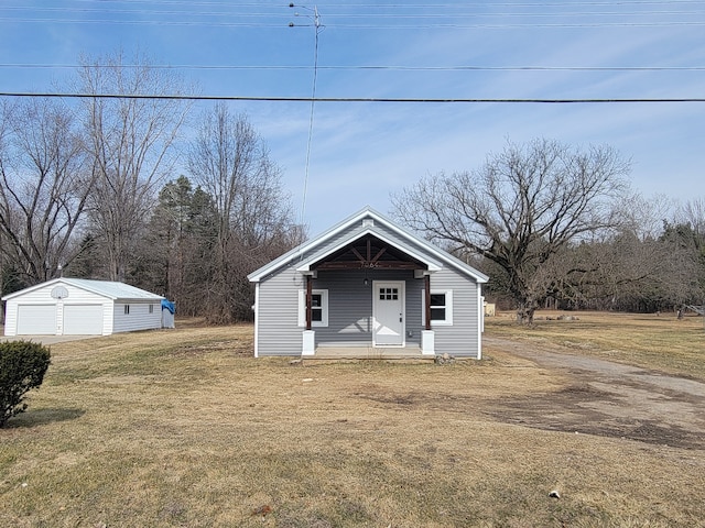 bungalow with an outbuilding, a front yard, a detached garage, and covered porch