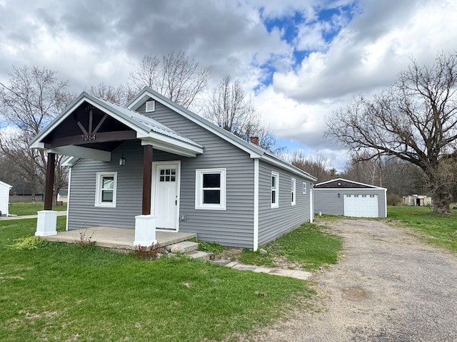bungalow-style house featuring an outdoor structure, a detached garage, dirt driveway, and a front lawn