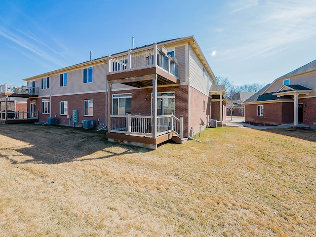 rear view of property featuring a balcony, cooling unit, brick siding, and a yard