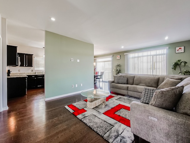 living room featuring dark wood-type flooring, recessed lighting, and baseboards