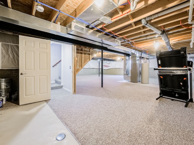 unfinished below grade area with heating unit, stairway, and gas water heater