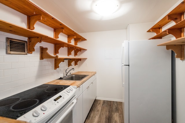 kitchen featuring open shelves, electric range oven, freestanding refrigerator, and a sink