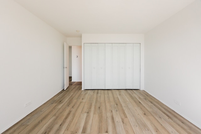 unfurnished bedroom with a closet and light wood-style flooring