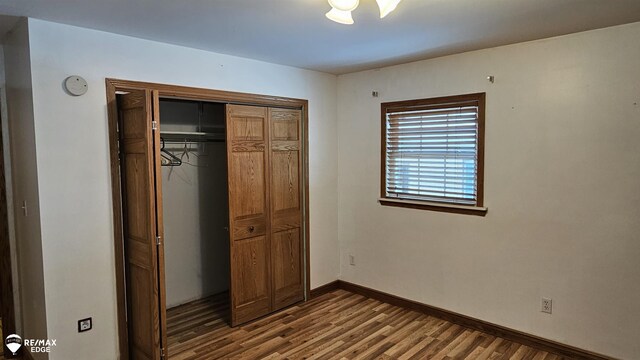 unfurnished bedroom featuring wood finished floors, a closet, and baseboards