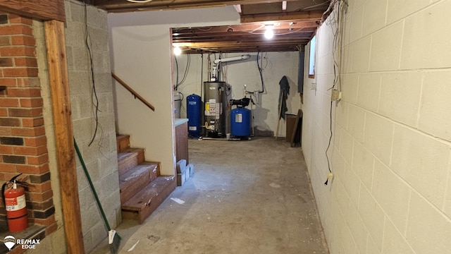 unfinished basement with water heater, stairs, concrete block wall, and a water pressure tank