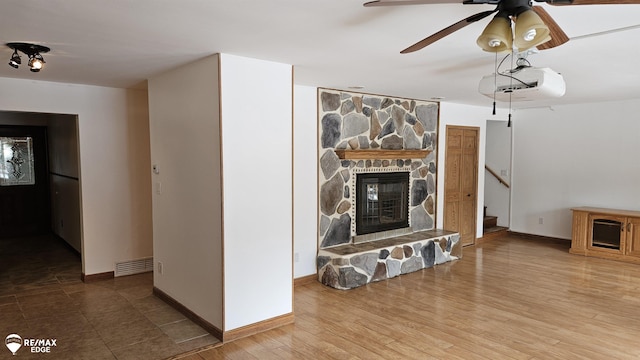 unfurnished living room with a ceiling fan, a fireplace, stairway, and baseboards