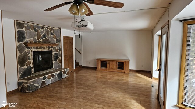 unfurnished living room with hardwood / wood-style floors, a ceiling fan, and baseboards