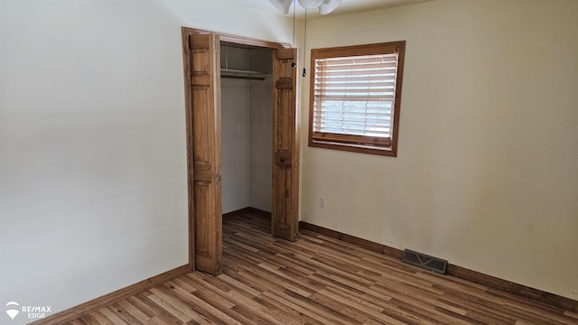 unfurnished bedroom featuring wood finished floors, baseboards, and a closet