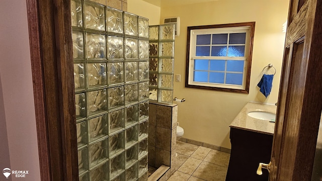 bathroom featuring tile patterned flooring, a walk in shower, toilet, and vanity