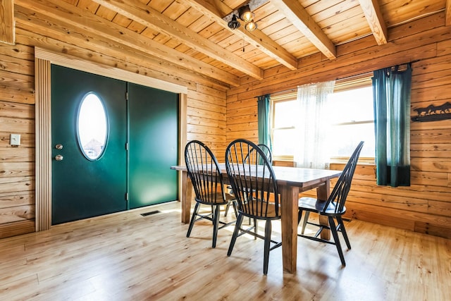 dining room with beam ceiling, wood walls, wooden ceiling, and light wood-style flooring