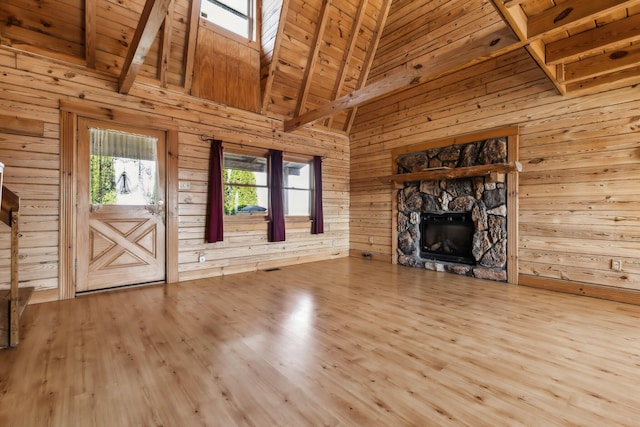 unfurnished living room featuring wood walls, wood ceiling, a stone fireplace, wood finished floors, and high vaulted ceiling