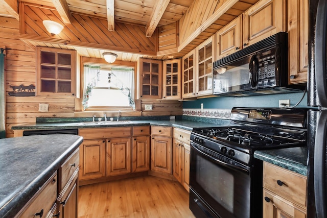 kitchen featuring wooden walls, a sink, black appliances, dark countertops, and wooden ceiling