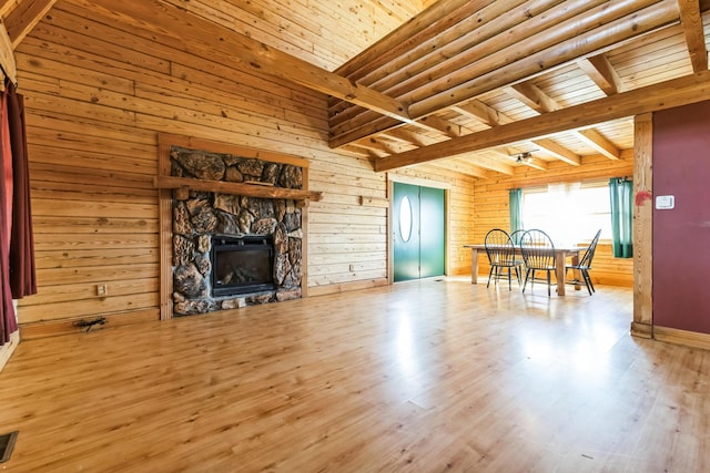 living area with wooden walls, beam ceiling, wooden ceiling, a fireplace, and wood finished floors